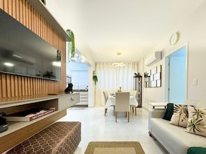 Una sala de estar moderna con televisión, sofá y comedor.