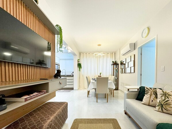 A modern living room with a TV, sofa, and dining area.