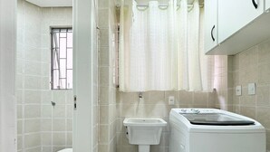 A compact bathroom with a toilet, sink, and washing machine. - Res. Villa de Collina-Centro de Floripa (Florianopolis)