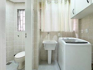 A compact bathroom with a toilet, sink, and washing machine.