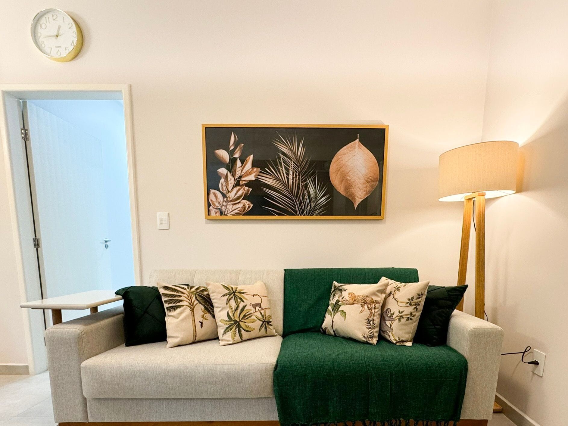 A living room with a sofa, green throw, and tropical-themed pillows.