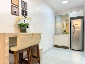 A modern kitchen with a stainless steel refrigerator, a bar stool, and a potted plant on the counter. - Res. Villa de Collina-Centro de Floripa (Florianopolis)