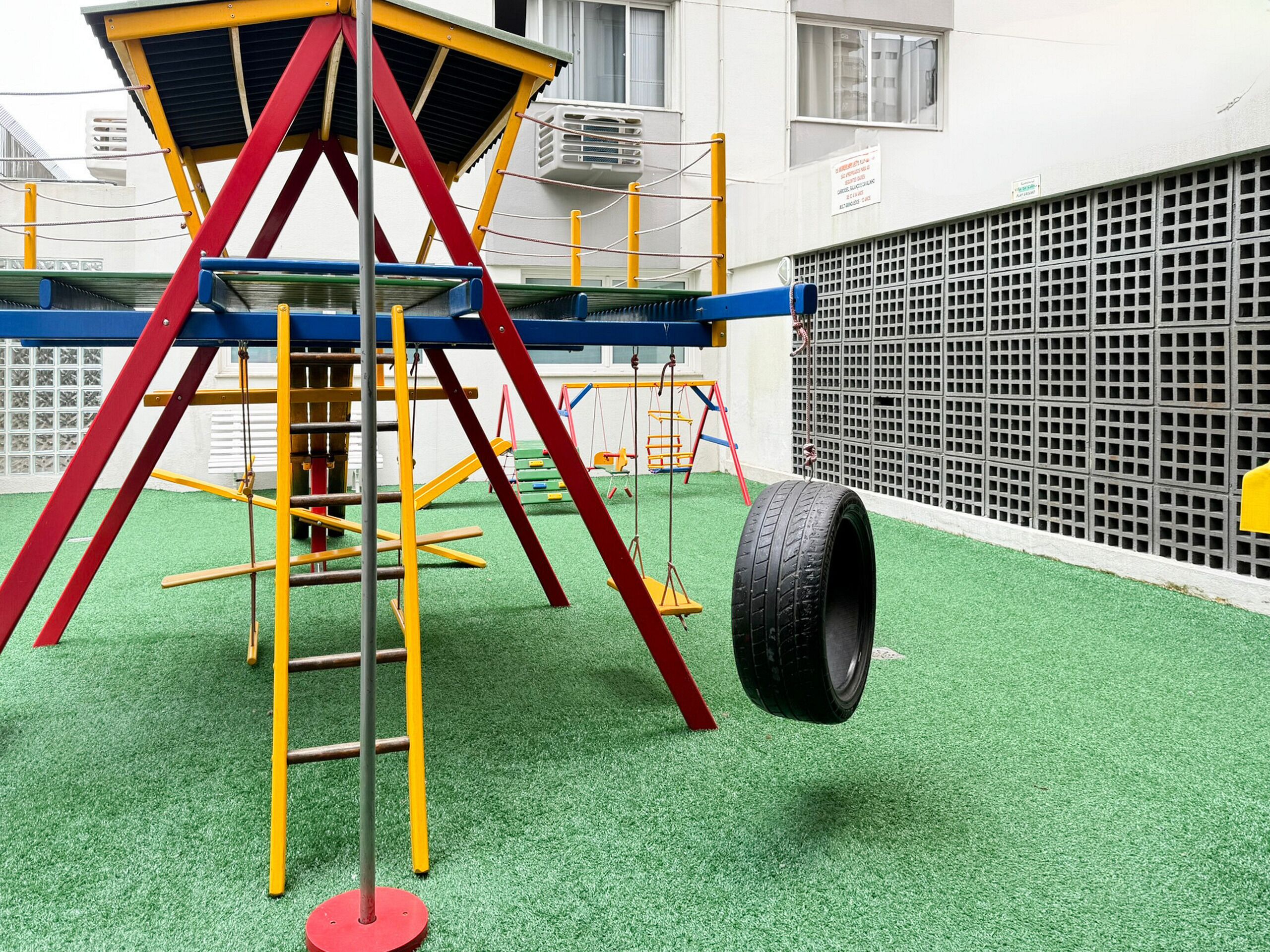 Une aire de jeux avec une structure d’escalade et une balançoire faite d’un pneu.