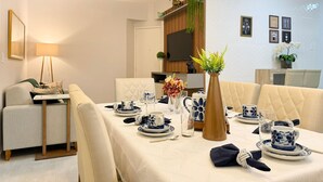 A dining area with a table set for four, a sofa, a TV, and a decorative plant. - Res. Villa de Collina-Centro de Floripa (Florianopolis)
