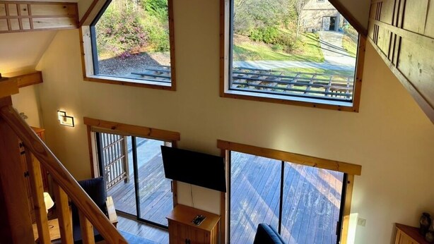 Ein Zimmer mit großen Fenstern, das Blick auf einen Garten und ein Haus bietet.