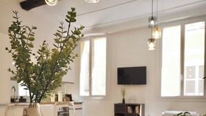 A dining area with a wooden table, a vase with green plants, wine glasses, and a black plate. - 06R - Nice modern apartment - Vieux Nice (Nice)