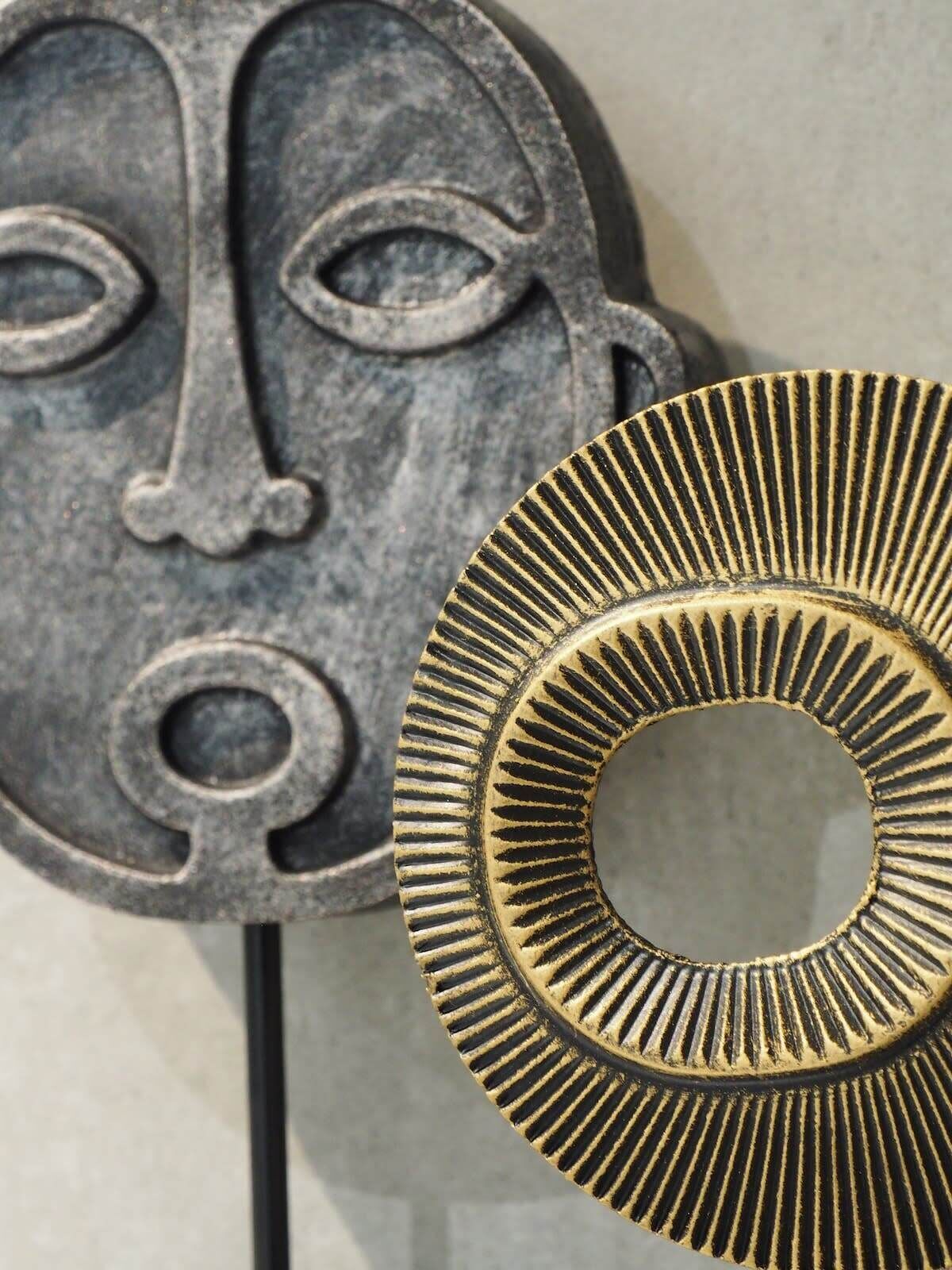 A metal sculpture with a circular design and a face-like structure.