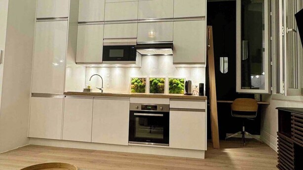 A modern kitchen with white cabinets, a built-in oven, and a microwave. There is a wooden table with a tray on it. - 06R - Nice modern apartment - Vieux Nice (Nice)