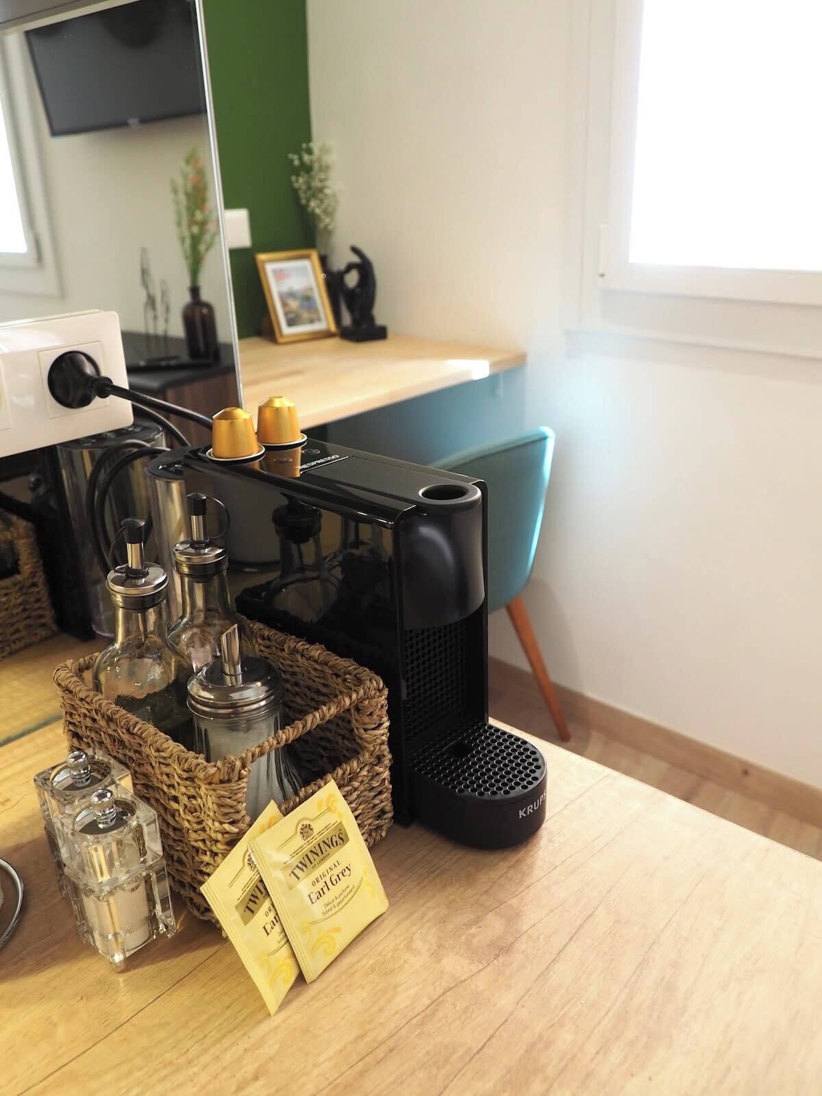 A kitchen counter with a coffee machine, a basket of glass bottles, and a package of Earl Grey tea.