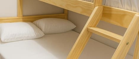 Una cama litera con escalera, almohadas y una manta.