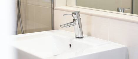 A bathroom with a white sink, chrome faucet, and a glass shower enclosure.