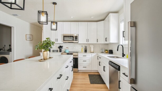 A modern kitchen with white cabinetry, a central island, a microwave, and a dishwasher.