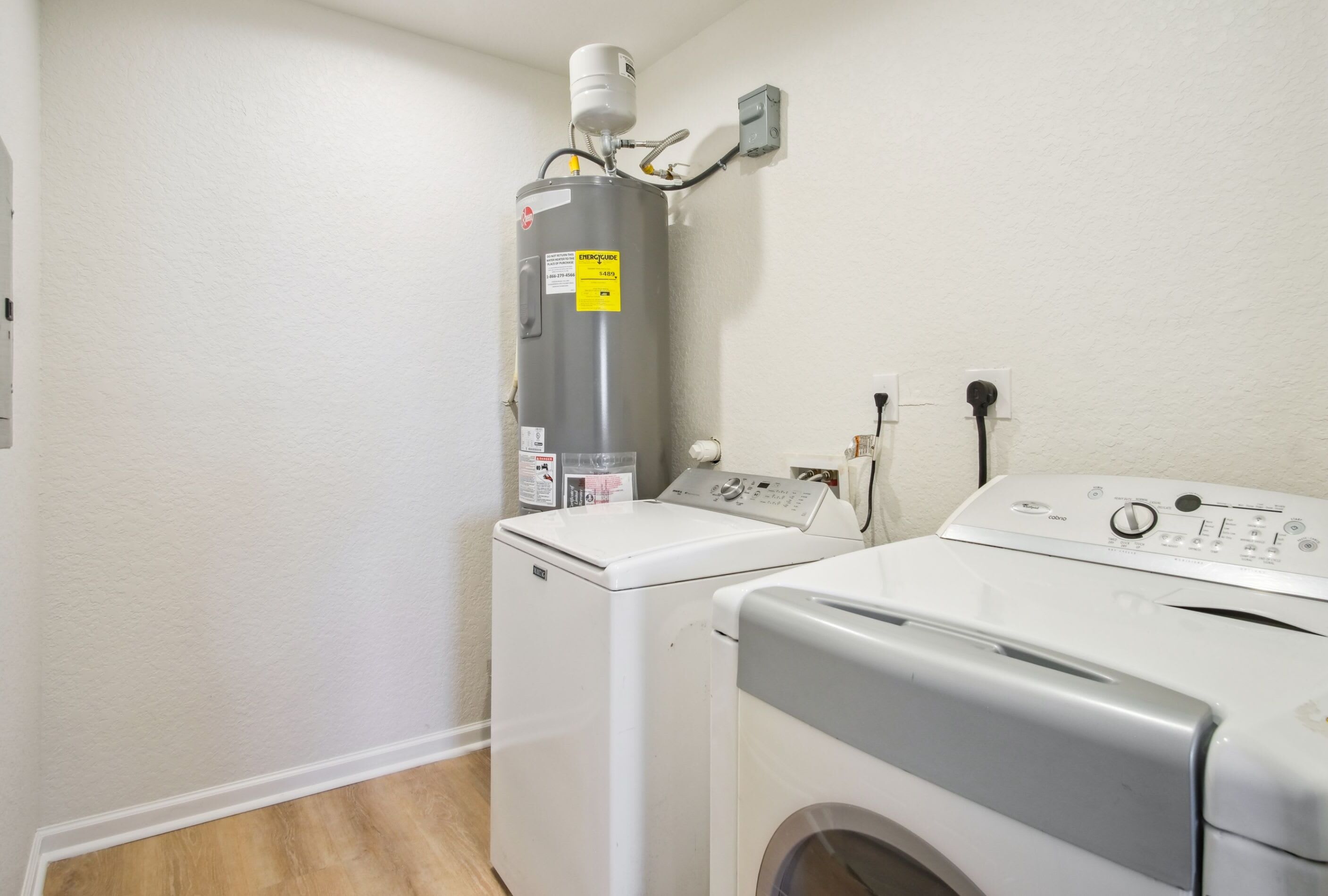 Une buanderie équipée d’un chauffe-eau, d’un lave-linge et d’un sèche-linge.