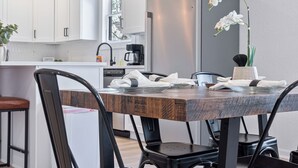 A modern kitchen with white cabinets, a stainless steel refrigerator, and a dining table with black chairs.