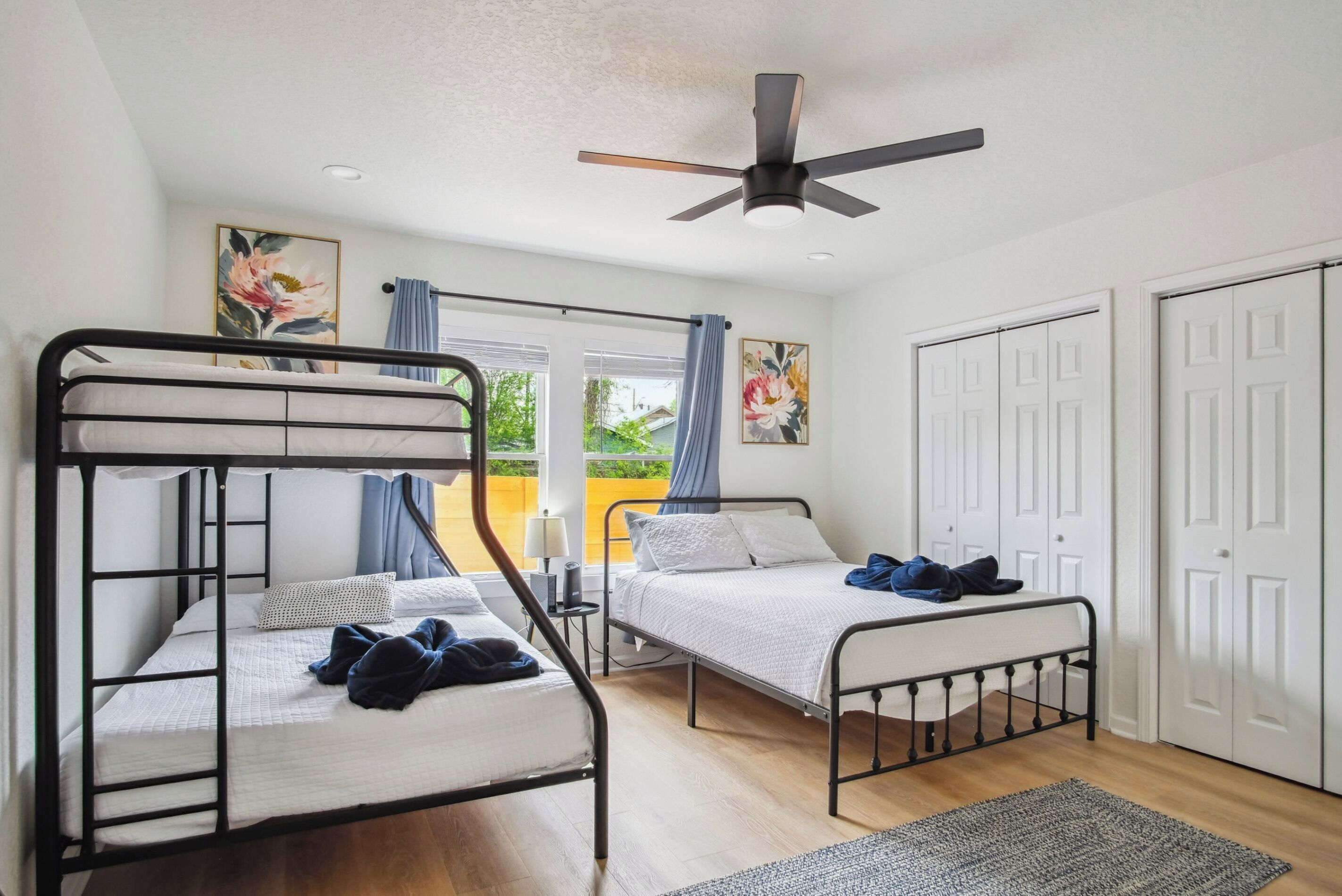 A room with two bunk beds, a ceiling fan, and a view of the outside.