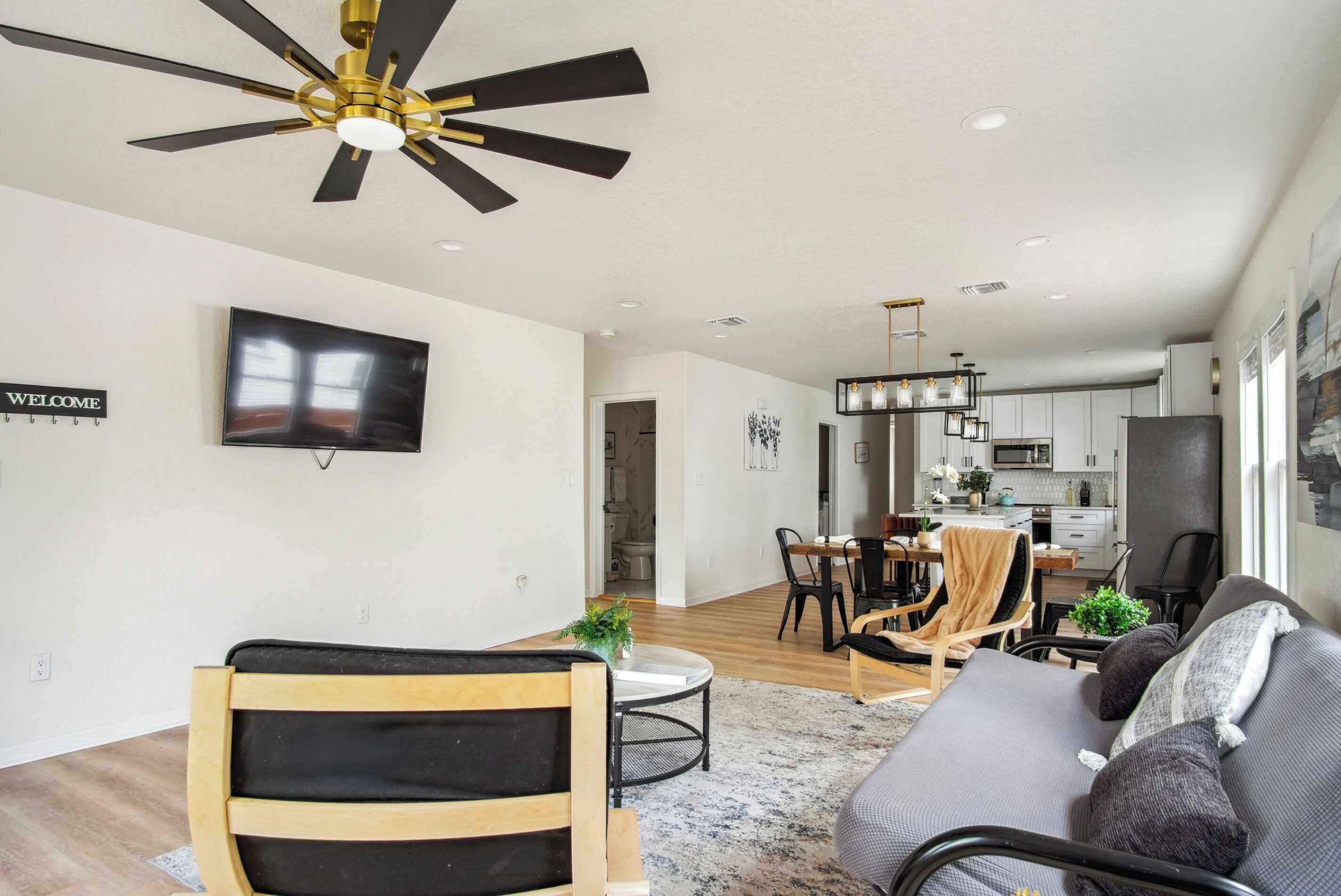 A modern living room with a sofa, a dining table, and a TV mounted on the wall.