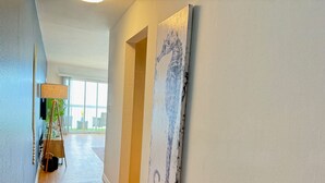 A hallway with a wooden floor, a lamp, and a painting on the wall. - Oceanfront Escape - Steps to Beach - Stunning Views & Balcony (Redondo Beach)
