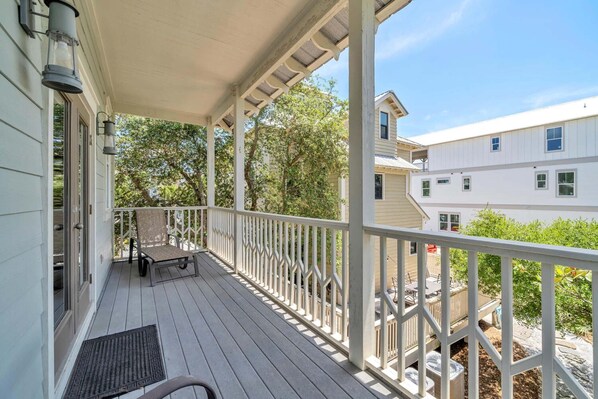 A covered porch with a bench, a door, and a view of neighboring houses.