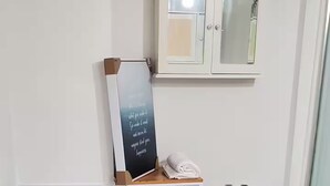 Ein Badezimmer mit Marmorfliesenrückwand, einer weißen Badewanne, einer Toilette und einem Schrank mit Spiegel.
