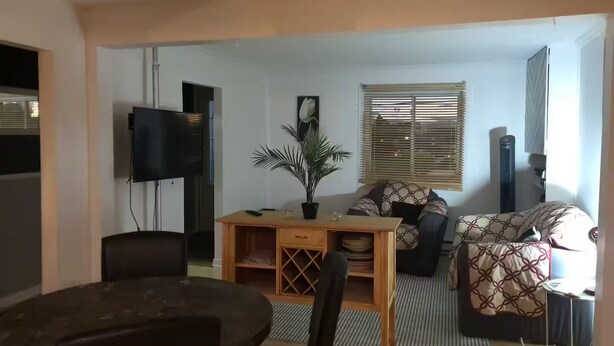 Ein Wohnzimmer mit einer Couch, einem Couchtisch, einem Fernseher und einer Pflanze.