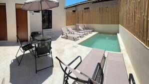 A pool area with lounge chairs, a table, and an umbrella. - Hotel Boutique Alcalá Vallarta (Puerto Vallarta)