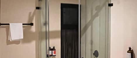 A bathroom with a glass shower enclosure, a toilet, and a wooden vanity with a sink.