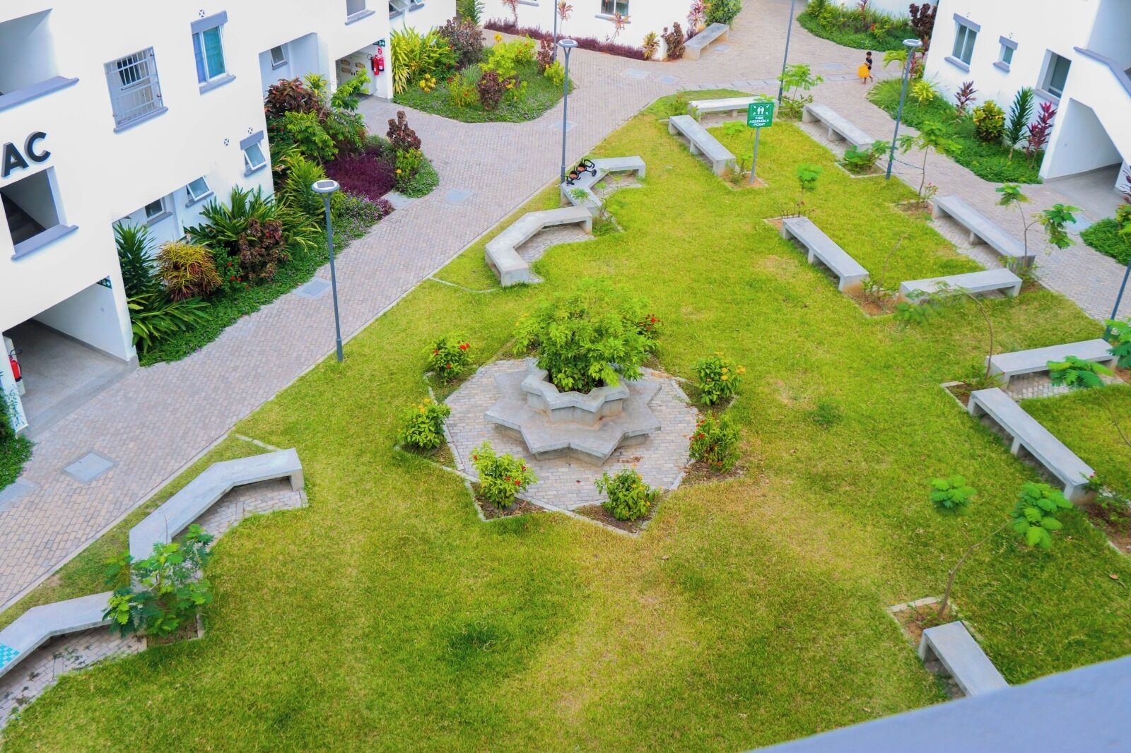 Un patio con jardín central, bancos y un sendero.