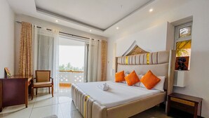 Een hotelkamer met een groot bed, een bureau, een stoel en uitzicht op de omgeving.