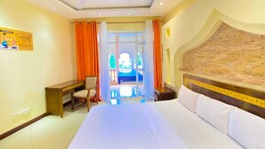 Hotelkamer met een bed, bureau, stoel, raam met gordijnen, plafondventilator en een stenen muur.