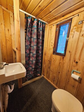 Ein Badezimmer aus Holz mit Waschbecken, Toilette und Fenster.
