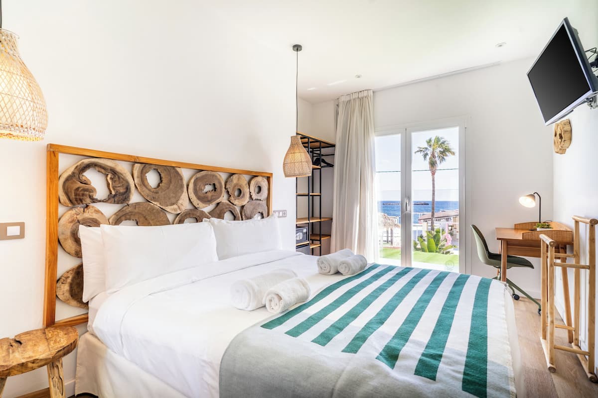 Una habitación de hotel con cama, escritorio, silla, televisor y vista al exterior.