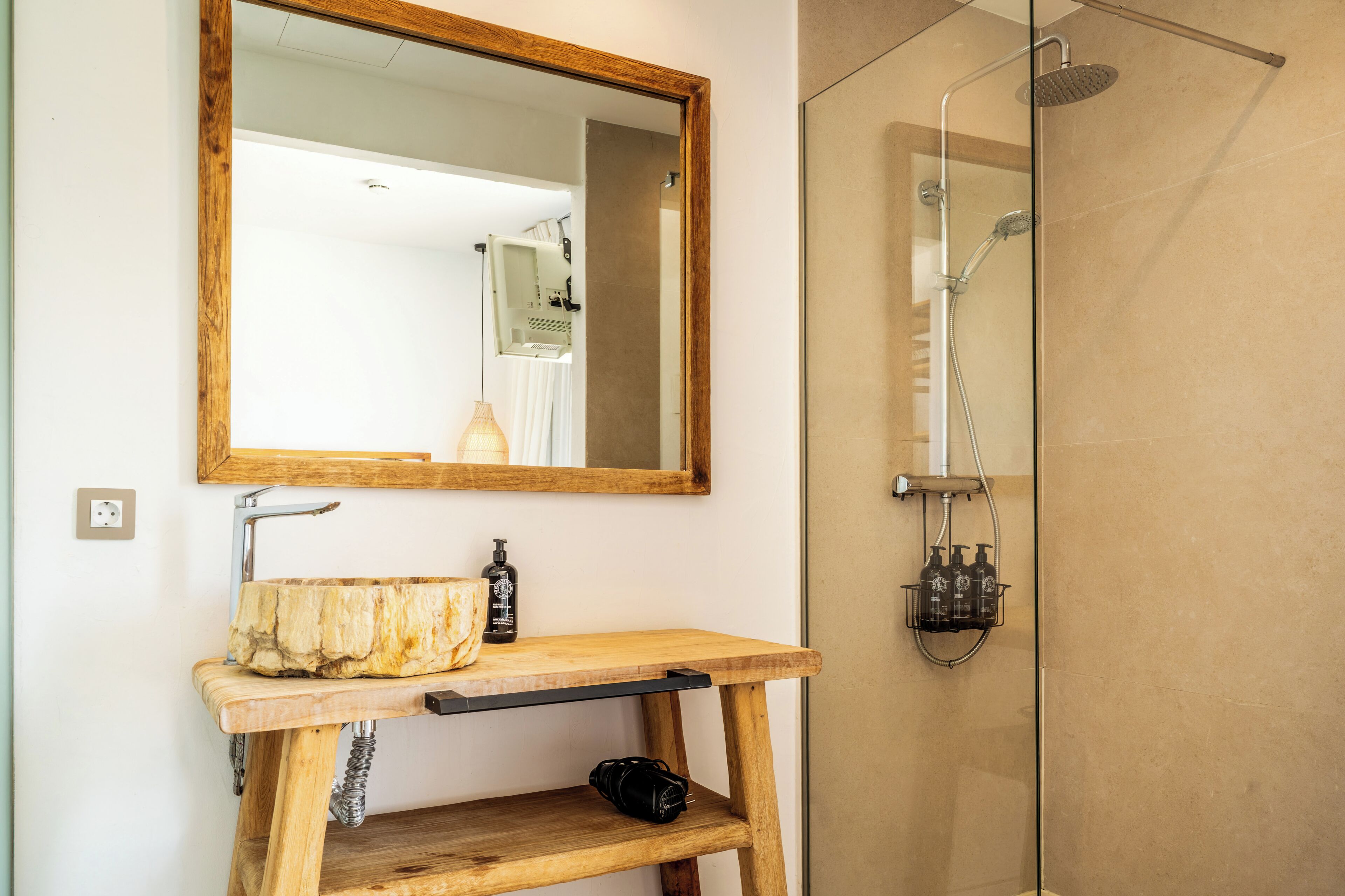 Ein Badezimmer mit Holztisch, Spiegel, Dusche und Waschbecken.