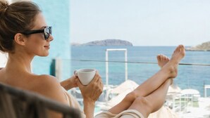 A person relaxing on a balcony with a view of the sea and a distant island. - Outsite Ibiza - Work, Connect, Explore (Santa Eulalia del Rio)