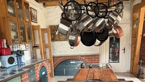 Una cocina con isla central, un colgador de ollas y un horno de ladrillo.