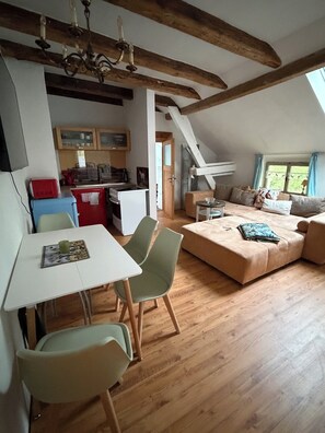 A loft-style room with a dining area, a sofa, and a kitchen. - Vacation cottage Siegstrand (Mittelhof)