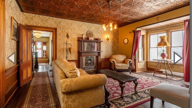 A traditional living room with a sofa, armchair, and a fireplace. - Heart of Pubnico (Pubnico)