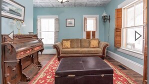 A room with a vintage piano, a sofa, and a red carpet. - Heart of Pubnico (Pubnico)
