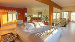 Un dormitorio amplio con una cama grande, un ventilador de techo y un balcón con vistas.