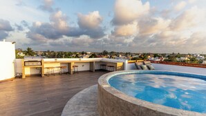Una terraza en la azotea con piscina, suelo de madera y zona de bar.
