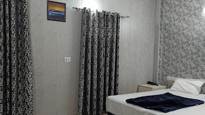 Een slaapkamer met een bed, nachtkastje, plafondventilator en kamergordijnen.