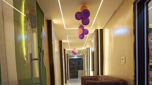 Een moderne hal met een glazen scheidingswand, een bank en een plafond met decoratieve verlichting.