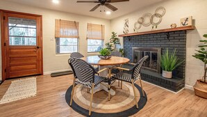 A dining area with a round table and four chairs, a ceiling fan, a fireplace, and a wooden door. - Charming Lake Front Home - Pet Friendly (Lake Norman of Catawba)