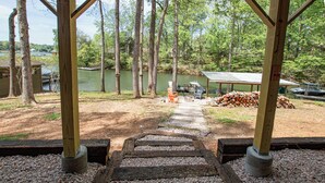 A wooden deck leading to a dock over a lake, surrounded by trees and a covered seating area. - Charming Lake Front Home - Pet Friendly (Lake Norman of Catawba)