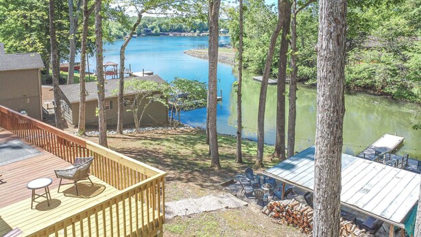 A deck with outdoor furniture overlooking a lake, surrounded by trees. - Charming Lake Front Home - Pet Friendly (Lake Norman of Catawba)