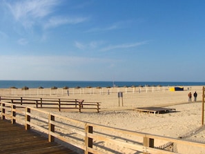 A beach with wooden walkways and umbrellas.