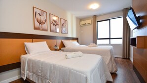 A hotel room with two beds, a TV, and artwork on the wall.