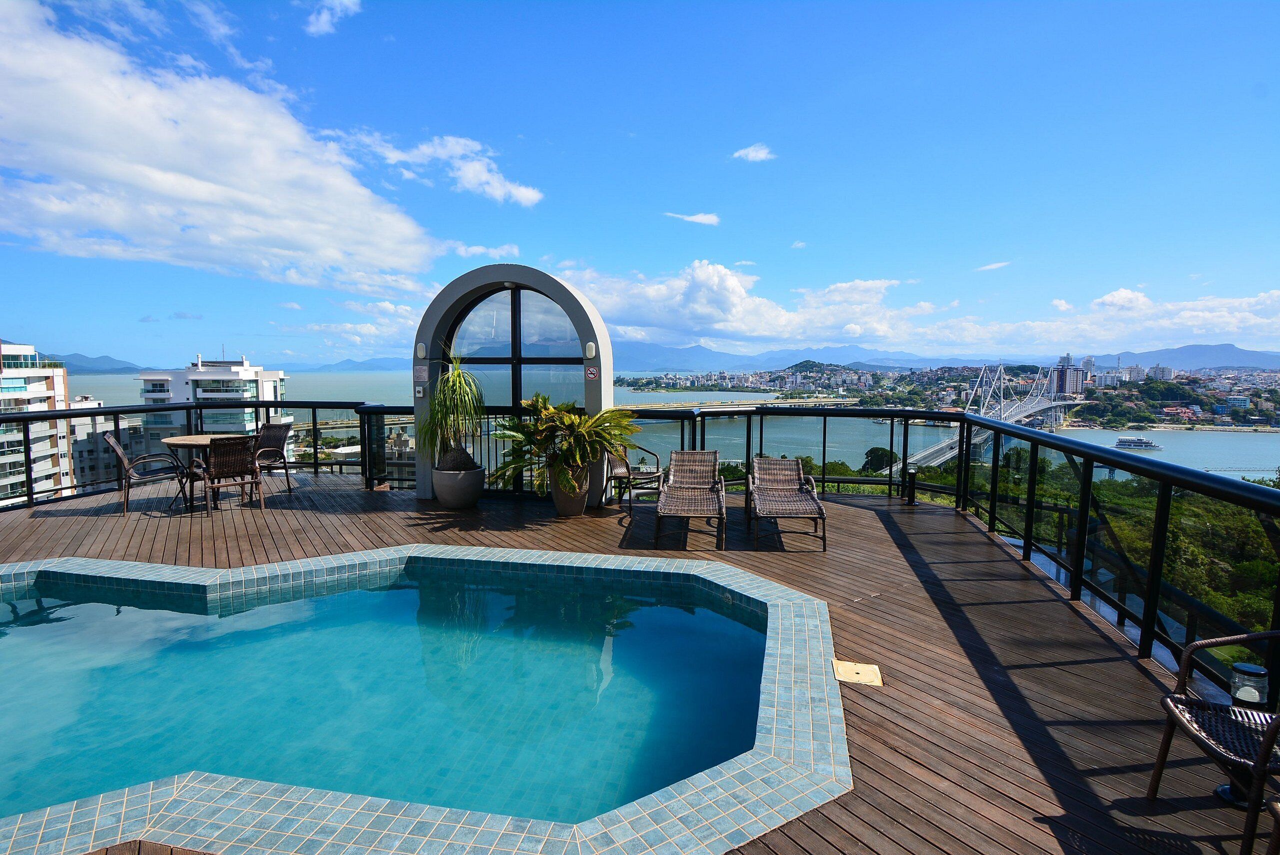 A rooftop pool area with a view of the city and a bridge.