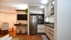 A modern kitchen with a built-in microwave, stainless steel refrigerator, and a flat-screen TV.