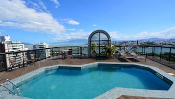 Una piscina en la azotea con vista al mar y un puente.