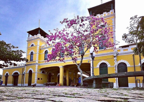 Un edificio amarillo con un patio central, arcos y una torre de campanas.